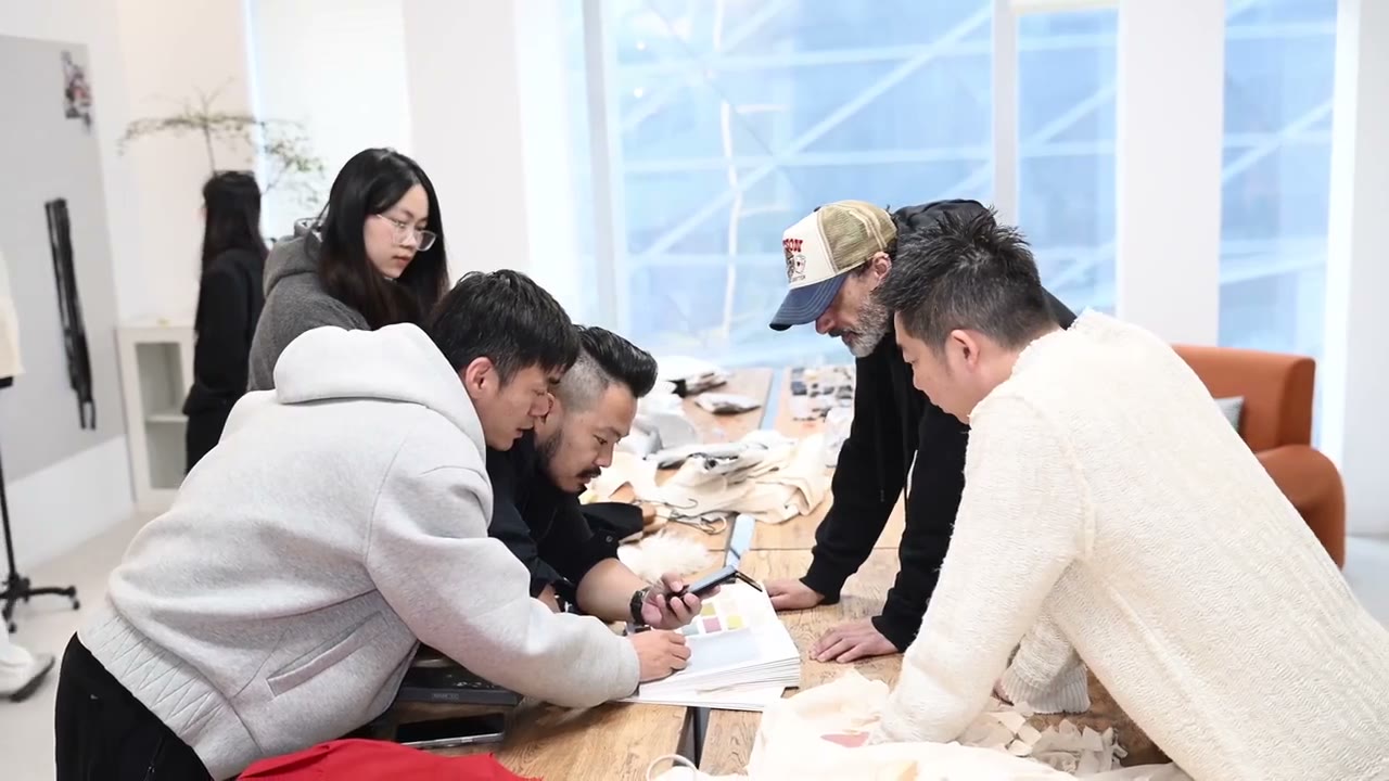 People comparing color cards around a table in supplied development footage